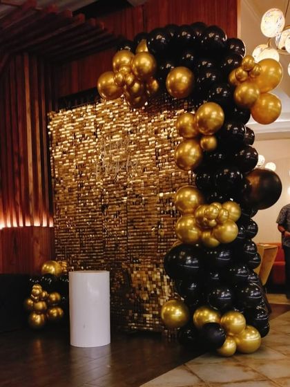 This black and gold theme is perfect for a glamorous party. The setup includes a full organic balloon arch against a gold shimmer sequin wall, creating a dramatic and high-impact photo booth.
