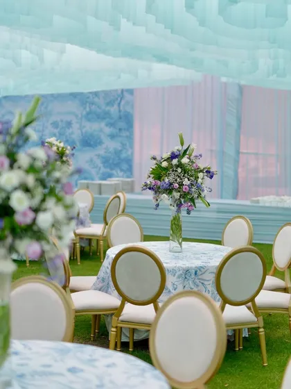 A closer look at the table decor for the Dior-themed event, where classic floral arrangements meet the custom blue and white patterned tablecloths for a sophisticated and cohesive look.