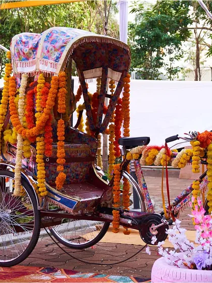 A quirky cycle rickshaw, fully decorated with colorful marigold garlands, serves as a fantastic photo prop and decor element for a fun-filled Haldi.