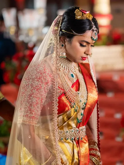 A bride during her wedding ceremony in a red and gold Kanchipuram saree. Her custom red blouse is fully embroidered with delicate beadwork.