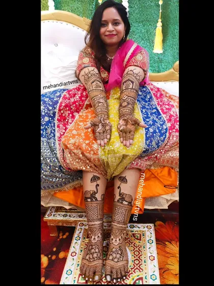 A complete bridal look includes beautiful mehandi on the feet as well. Here, you can see how the designs on the hands and feet complement each other, featuring traditional elephant and architectural motifs.