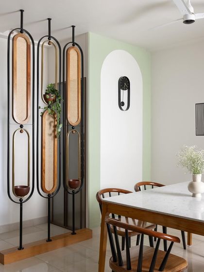 To create a dedicated puja space in the dining area, I designed this movable partition made of cane, brass, and wood. It separates the space beautifully without blocking light, and includes built-in planters.