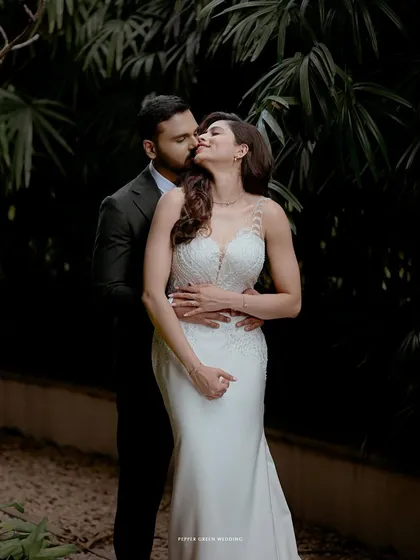 A romantic embrace in a lush garden setting. The contrast between the dark background and the couple's attire makes this a striking and passionate portrait.