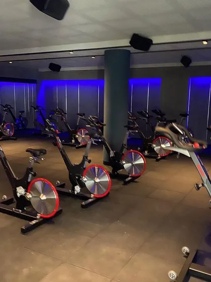 For the Chakra spinning studio, we created a high-energy, immersive environment. The use of dynamic blue ambient lighting against dark walls and industrial-style flooring sets a motivational tone for intense workouts.