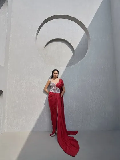 This look reimagines the sari with a deep crimson drape sculpted by a hand-embellished pearl corset belt. It is a fusion of Indian elegance and contemporary couture for the woman who bends tradition to her will.