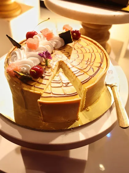 A stunning caramel cheesecake with a spiderweb drizzle, sliced and ready to be served.