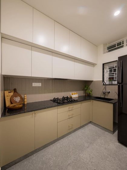 A practical and elegant kitchen design with a neutral color palette. The combination of beige and white cabinets with a black granite countertop creates a timeless look.