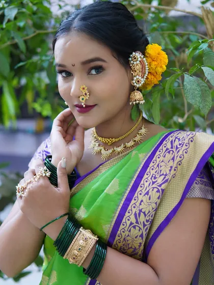 A vibrant look with a green Paithani saree and bold lip. The yellow flowers in her hair add a beautiful traditional contrast, perfect for a daytime wedding ceremony.