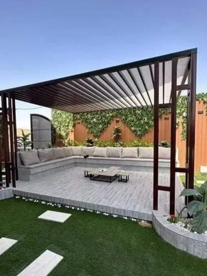 A modern pergola with a slatted roof over a built-in seating area. This design is perfect for creating a comfortable lounge space next to a lawn or pool.