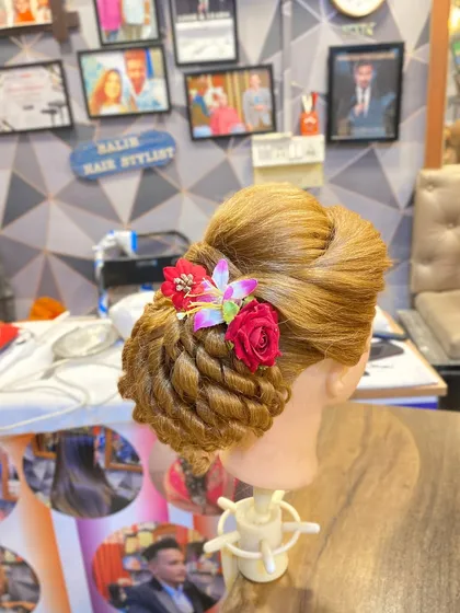 A different angle of the student's floral bun, showing the intricate twisted pattern. Students practice these techniques on mannequins to perfect their skills.