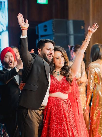 Pure celebration! The bride and groom with their hands in the air, enjoying the applause after a fantastic performance.