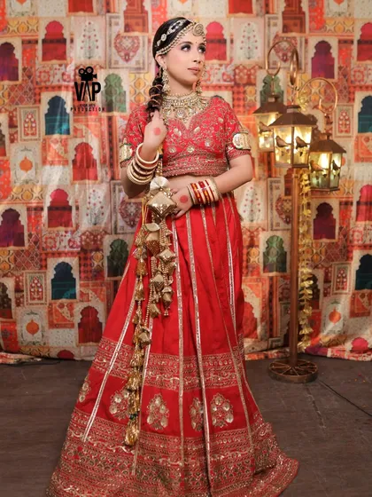 This is a full view of a traditional Rajwadi bridal lehenga. Notice the rich red fabric, the detailed golden embroidery on the skirt and choli, and the way it creates a perfect silhouette. This is the kind of outfit that makes a statement.
