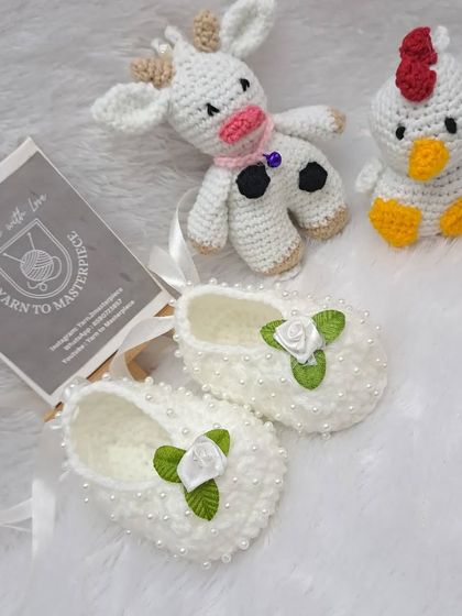 This farm-themed baby gift set includes a little cow, a chick, and a pair of beautiful white booties decorated with pearls and roses.