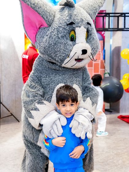 A young guest gets a hug from a life-sized Tom mascot, a perfect photo opportunity and a cherished memory.