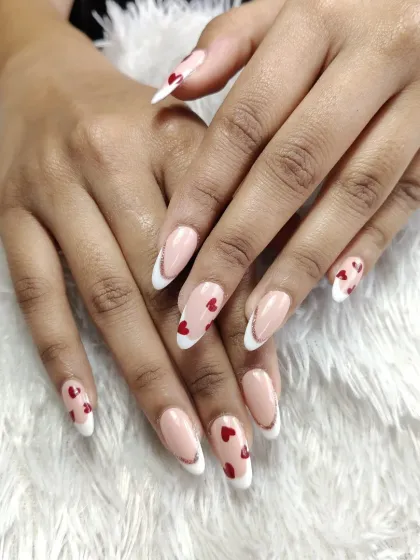 A sweet and modern take on the French manicure. This design features classic white tips on almond-shaped nails, with accent nails adorned with tiny, hand-painted red hearts.