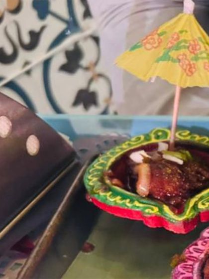 A festive presentation of a savory appetizer served in a decorative diya with a cocktail umbrella, showing our creative flair for special occasions like Diwali.