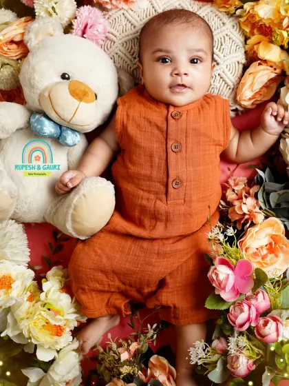 This two-month-old baby is sharing a moment with his fluffy friend. We use props like teddy bears to make babies feel comfortable and happy.