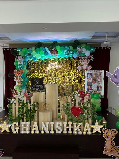 A sweet jungle animal theme with a gold shimmer wall and a green balloon arch. The setup includes panda, leopard, and elephant cutouts, along with personalized marquee letters.