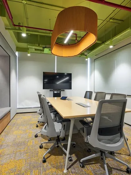 This meeting room features a window-seat for a more relaxed feel, a large whiteboard, and a unique pendant light. The green and yellow color scheme is energetic and positive.