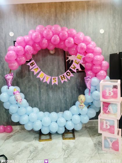 A classic pink and blue baby shower balloon ring. This setup includes a 'Baby Shower' banner and transparent 'BABY' blocks, perfect for a gender reveal party.