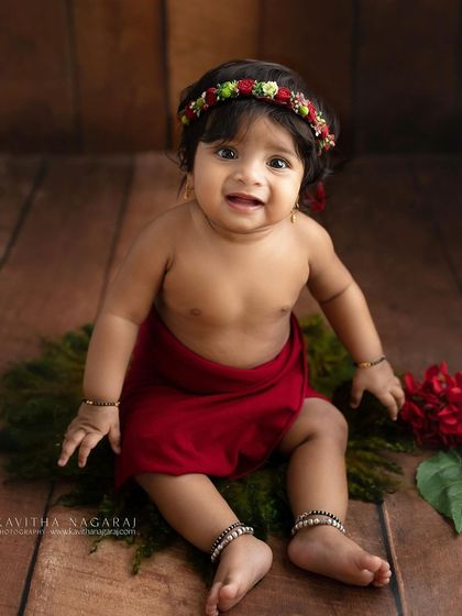 A happy seven-month-old sitting on a bed of moss. The natural elements and her bright smile create a joyful and earthy portrait.