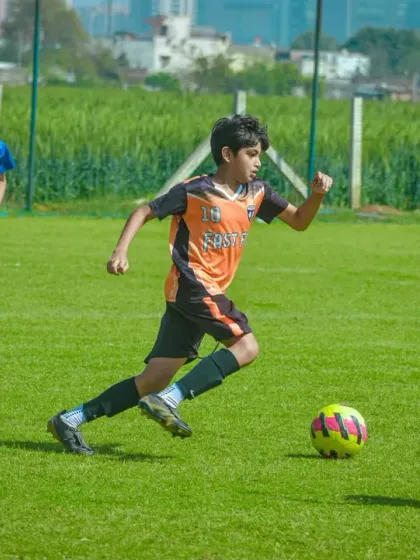 A player sprints with the ball during the Pride Cup Gurgaon Edition, with the city skyline in the background.