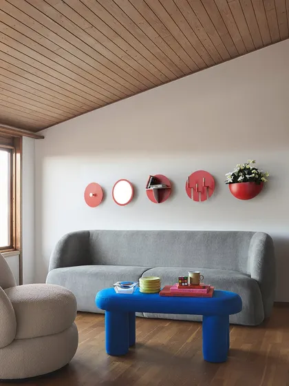 Our Aabhla collection reimagines the traditional Lipan Kaam craft of Kutch for modern interiors. This wall display features a composition of circular mirrors, shelves, and planters, adding a vibrant, culturally rich focal point to a contemporary living space.