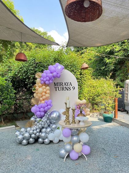 An elegant outdoor birthday party for 'Miraya turns 9' with a purple, peach, and silver color scheme.