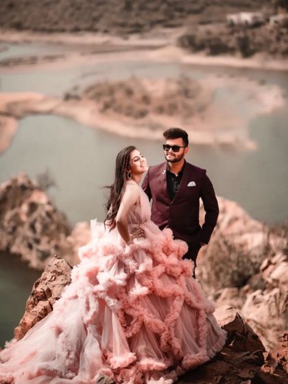 This is what fairytale pre-wedding shoots are made of. The couple is posed on a dramatic cliffside, with her gorgeous pink gown creating a stunning visual against the natural backdrop.