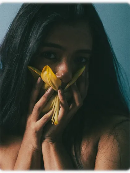 A playful and slightly surreal shot where the model holds the flower petals to her mouth. It's an unconventional pose that sparks curiosity and adds an artistic flair to the beauty series.