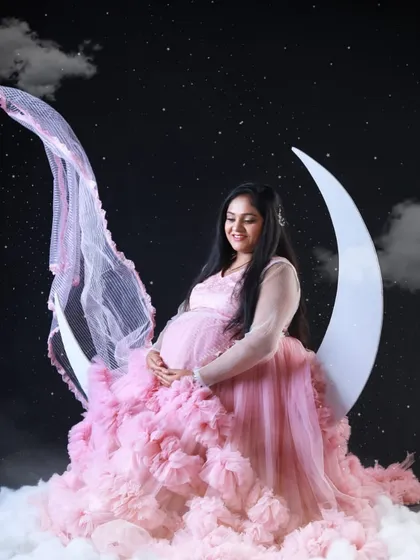 "Over the moon" about the new arrival. This creative studio shoot uses a moon prop, with the pink ruffled gown adding to the celestial, dreamy vibe.
