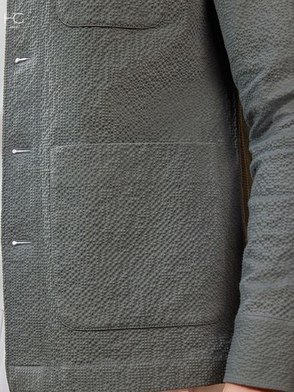 A detail shot of the textured fabric on the olive green shacket, highlighting the craftsmanship and quality that goes into every piece.