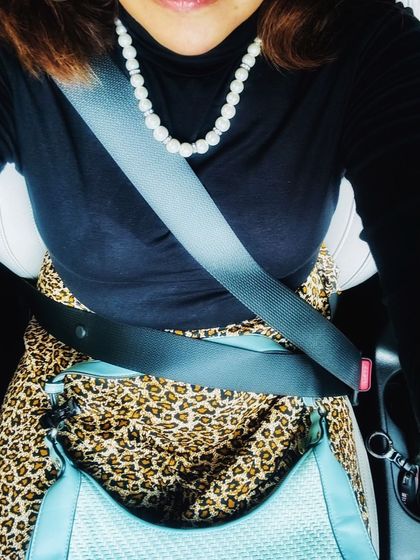 A car selfie focusing on the details. The classic pearl necklace adds a touch of timeless elegance to the black turtleneck and leopard print skirt, showing how jewelry can refine a look.