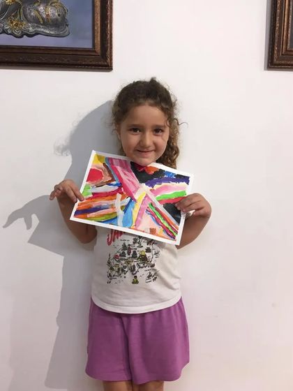 A young artist shows off her fantastic abstract expressionist painting, a canvas full of energy and color.