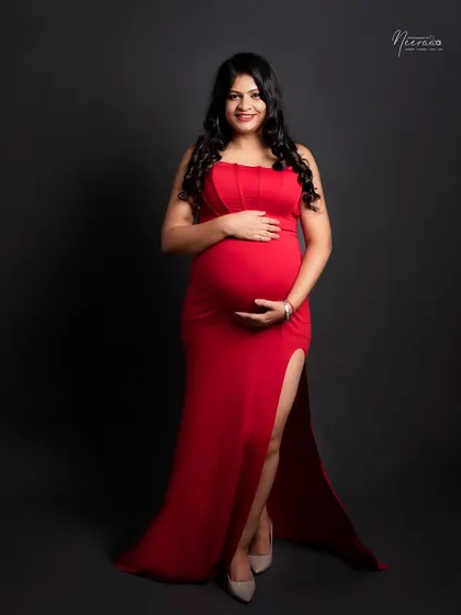 A full-length portrait showcasing a stunning red gown. Her confident pose and direct gaze make this a powerful and beautiful image of motherhood.
