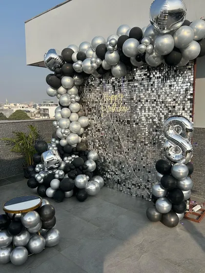 This stunning rooftop setup for a birthday featured a glamorous silver sequin wall, a black and silver balloon arch, and a comfortable, low-seating arrangement under a canopy of fairy lights. It was the perfect blend of chic and cozy for an evening celebration.