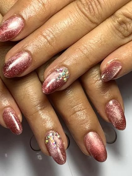 A beautiful rose gold cat eye polish on medium-length nails. This set is accented with clusters of small crystals for an extra touch of sparkle and luxury.
