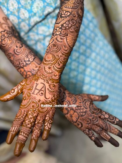 A beautiful view of the 'H' initial mehendi, showing the intricate patterns covering the arms.