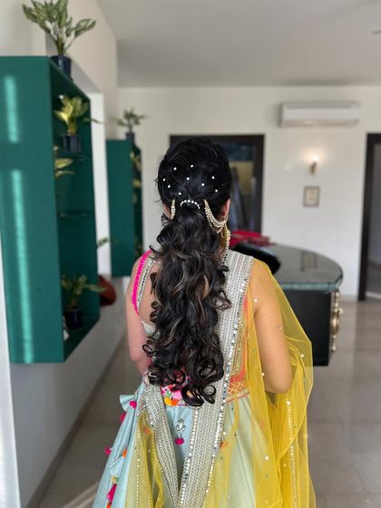 The full look, showing how the accessorized ponytail pairs with a colorful mehndi outfit.