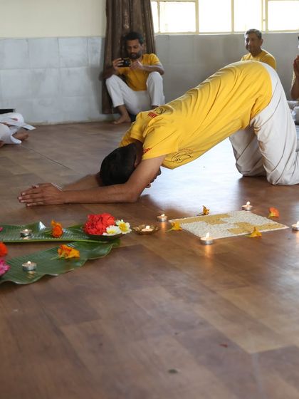 A student performs Sashtanga Namaskar before the graduation altar, decorated with flowers and candles, to honor the spiritual masters.