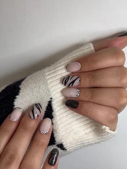 An edgy and chic set featuring zebra print, a silver chain-link accent, and black glitter nails. This design mixes multiple textures and patterns for a unique look.
