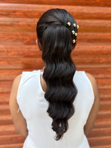A clear back view of the stylish wavy ponytail with gold bead accents.
