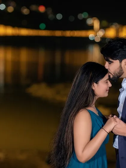 A gentle forehead kiss against the beautiful bokeh of the Ram Jhula bridge lights at night. This is a classic romantic shot that captures the quiet intimacy and beauty of Rishikesh after dark.