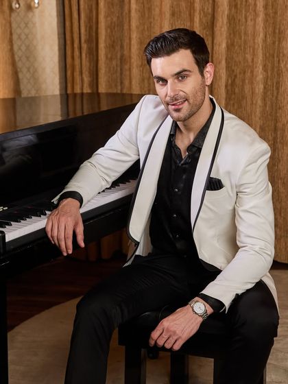 Seated at the piano, this shot shows how a bespoke tuxedo moves with you. The white jacket maintains its structure without feeling stiff, ensuring comfort throughout your event.