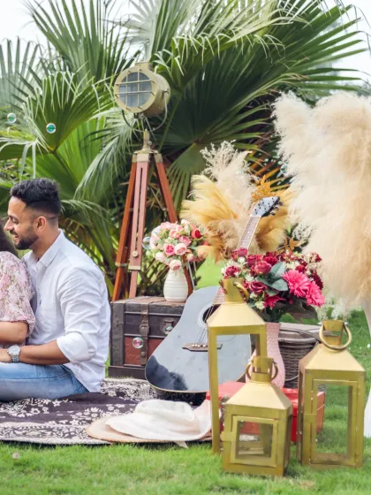 A close-up of the bohemian-styled picnic. Details like pampas grass, a vintage spotlight, and a guitar add a personalized and artistic touch to the couple's pre-wedding shoot.