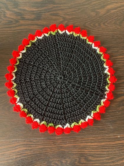 A top-down view of the black doily with a red tulip border.