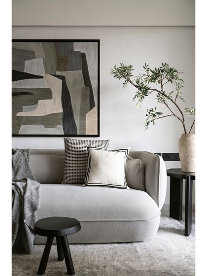 A close-up of the custom angular sofa in the Noir Blanc House. The light grey boucle fabric and curated cushions create a look of understated luxury and comfort.