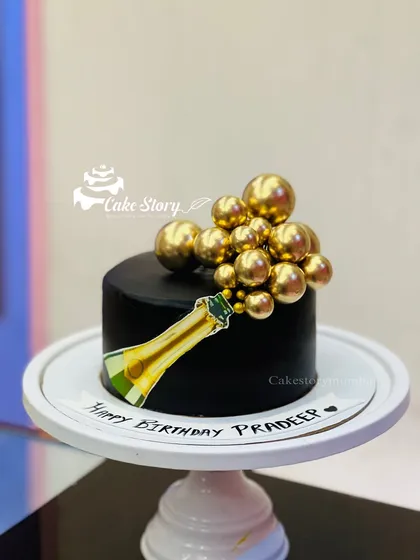 A chic and celebratory champagne-themed cake. The black cake is decorated with a champagne bottle print and golden bubbles, perfect for a sophisticated birthday or milestone.