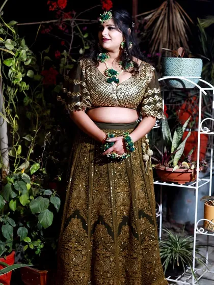 A beautiful outdoor portrait of the bride on her Mehndi day. The natural greenery complements her olive green lehenga and floral jewelry perfectly.