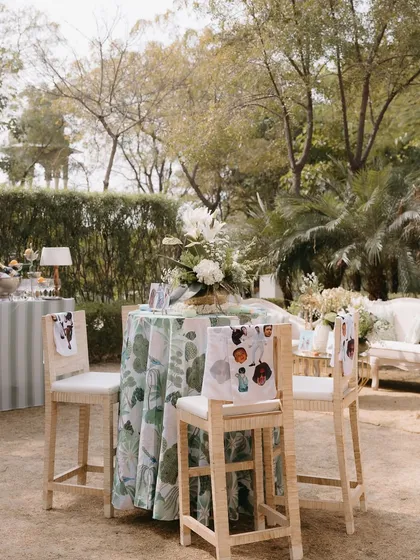 A high-top table at a luncheon, with custom-printed fabric on the chair backs. These small details add a layer of bespoke design that makes the event feel truly unique.